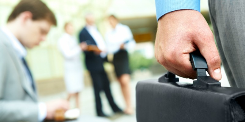 Close-up of businessman hand holding briefcase in working environment